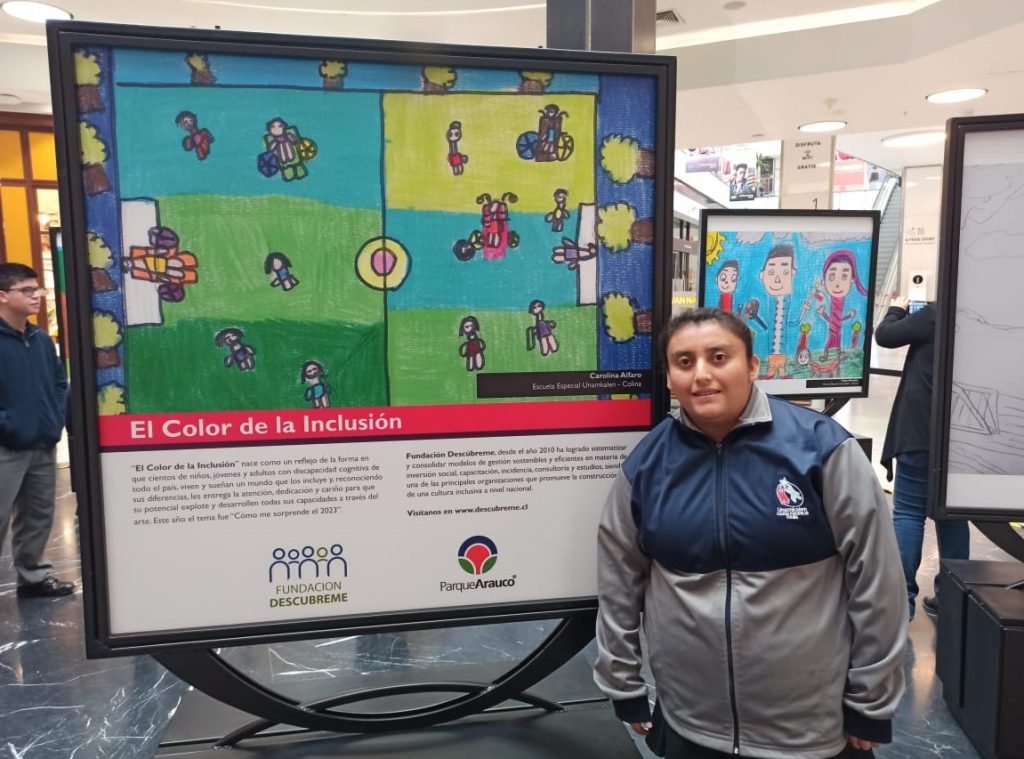 Imagen de Carolina Alfaro, primer lugar en “El Color de la Inclusión 2022” posando junto a su obra.