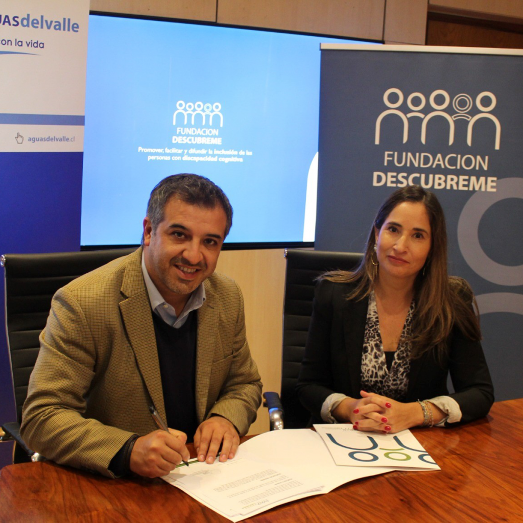 Imagen de dos personas firmando un acuerdo, un hombre gerente de Personas y Asuntos Corporativos de Esval, Jaime Henríquez. y una mujer Soledad Lara, subgerente Comercial de Fundación Descúbreme.