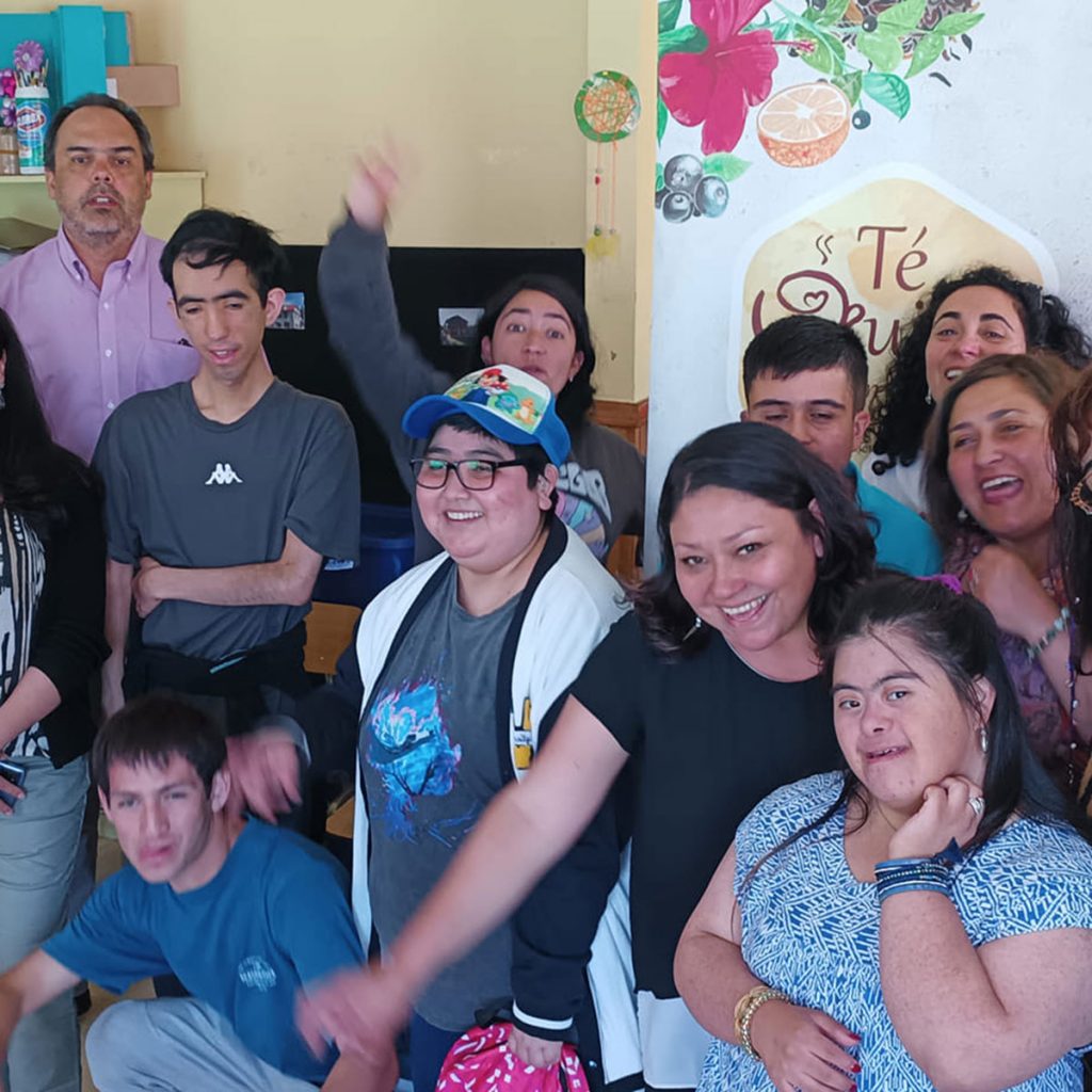 Grupo de personas de la organización y beneficiarios miran sonriendo a ala cámara 