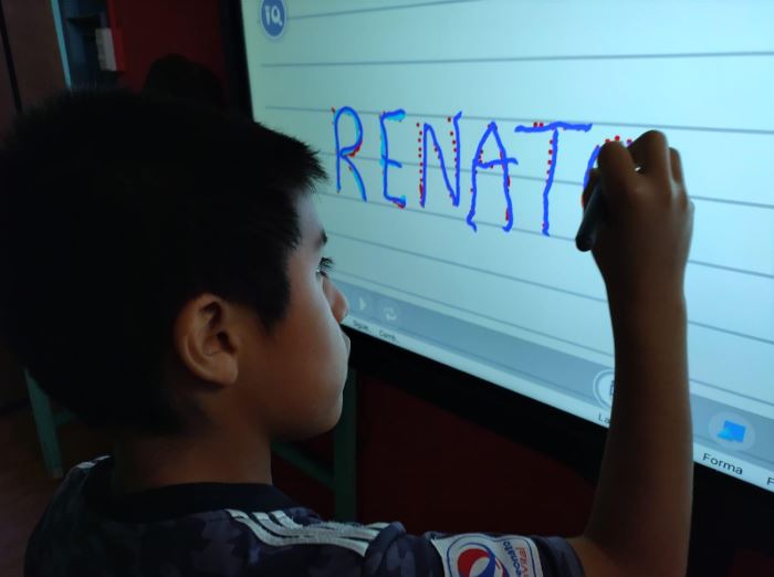 Niño escribiendo en una pantalla digital 