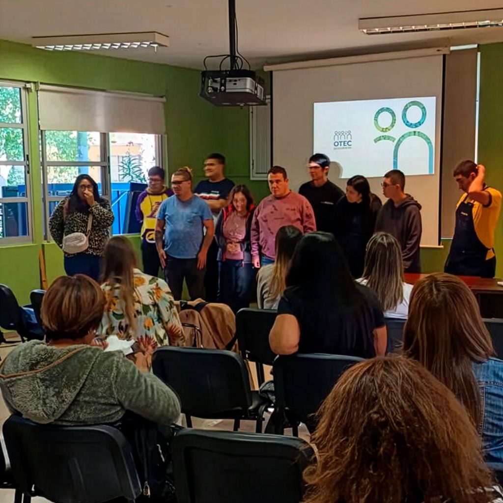 Personas al frente de una sala durante el inicio de una actividad del curso de Administración de Bodega, mientras asistentes observan sentados. Al fondo se ve una pantalla de proyección.